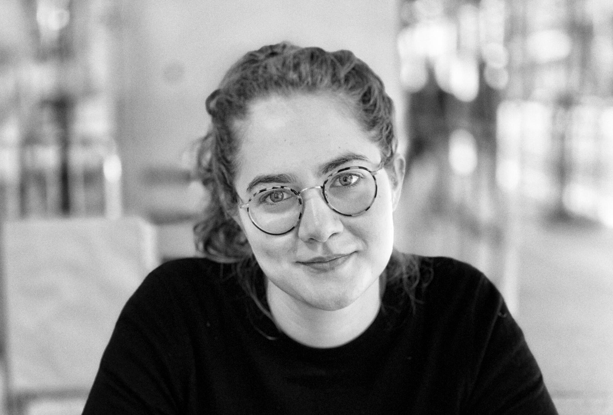 A black and white close-up of Maria McIndoo smiling at the camera.